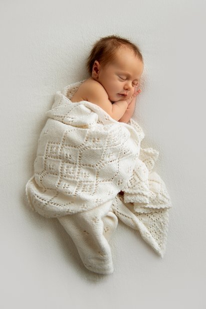 nyfødt baby sover søtt med babyteppe